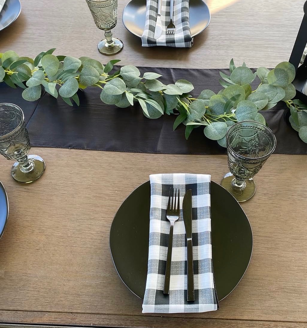 Close-up of an elegant table setting with eucalyptus garland and buffalo check napkins