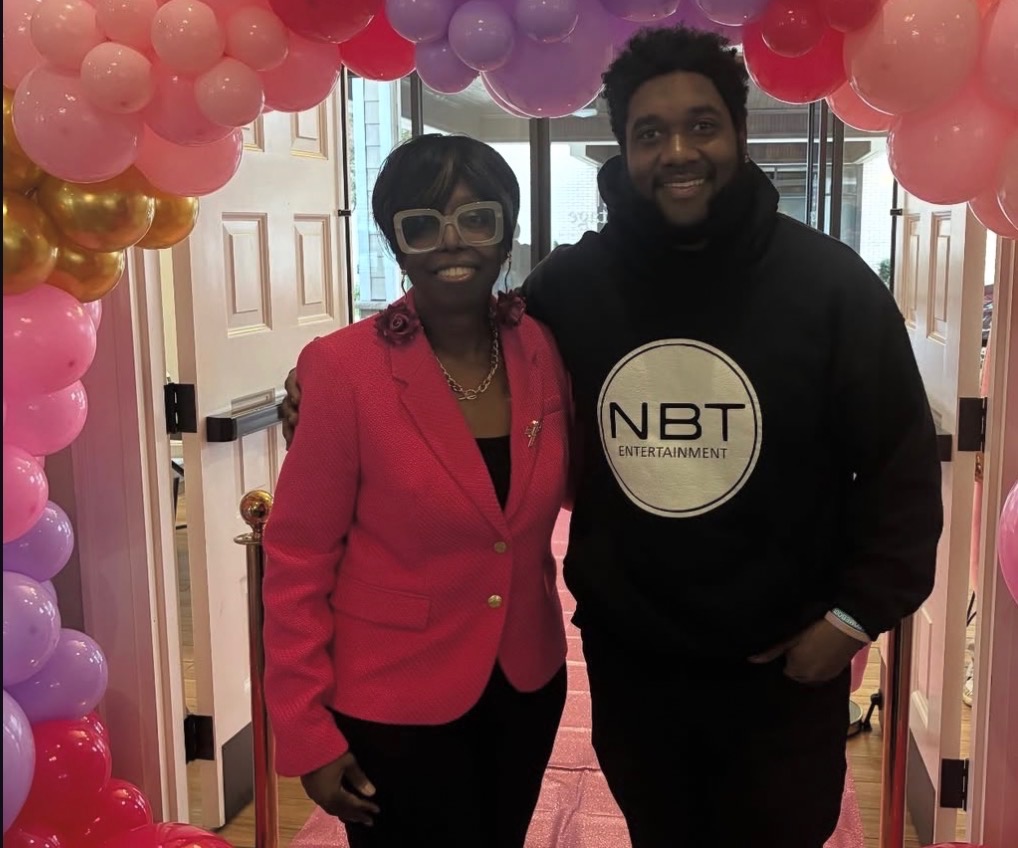 NBT Entertainment host with a guest under a pink and purple balloon arch