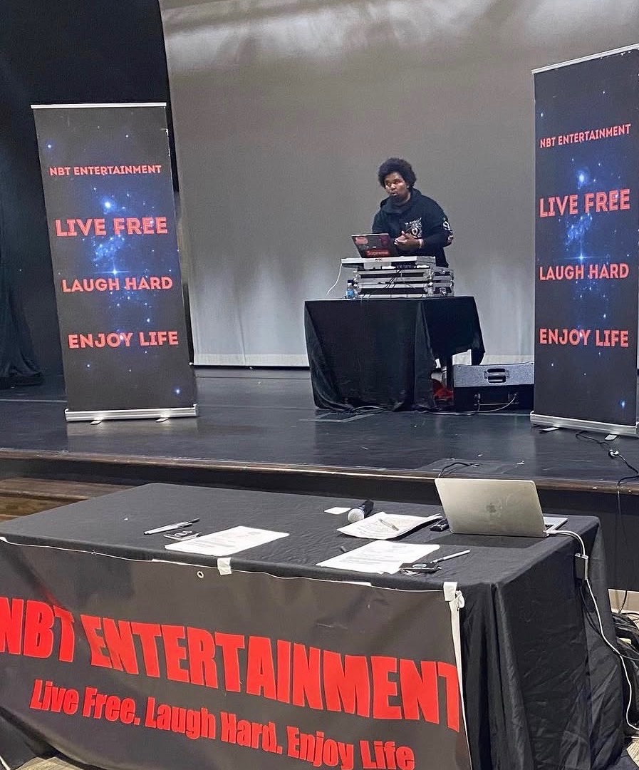 NBT Entertainment DJ performing on stage with branded banners