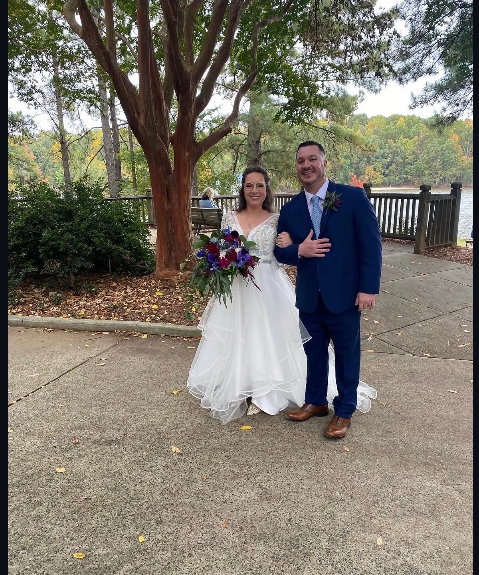 Bride holding bouquet with groom at a lakeside fall wedding